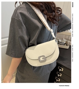 Dettaglio della borsa a sella in pelle bianco crema con fibbia G e tracolla jacquard