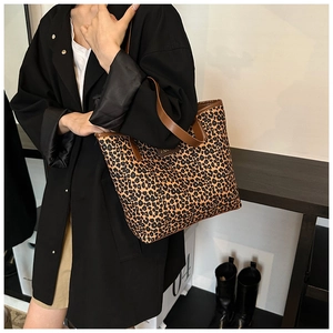 Detail of leopard print tote bag featuring brown leather straps and fashion label detail