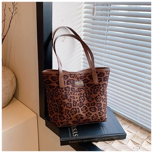 Detail of leopard print tote bag featuring Fashion label on a textured brown surface