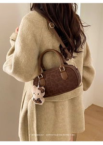 Dettaglio di una borsa minimalista leopardata con ciondolo in peluche e tracolla in pelle