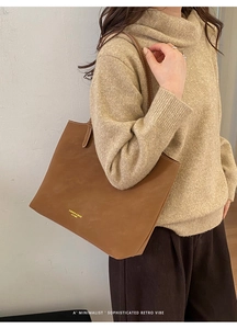 Gros plan du cabas vintage en cuir marron avec texte doré et fines surpiqûres blanches