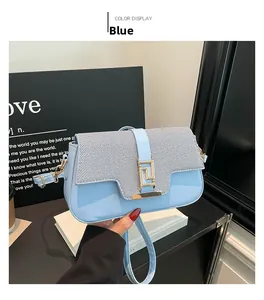 Detail of light blue saddle bag featuring glossy leather and textured fabric stitching