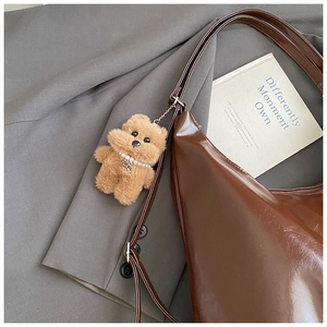 Detailed macro view of deep brown faux leather tote with a cute plush bear charm accessory