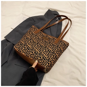 Detail of leopard print tote bag featuring brown leather base and metallic fashion tag