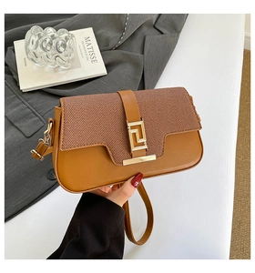 Detail of caramel patchwork saddle bag with woven texture lid and golden geometric clasp