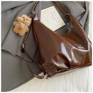 Close-up of a large dark brown polished tote bag with a cute plush bear charm detail