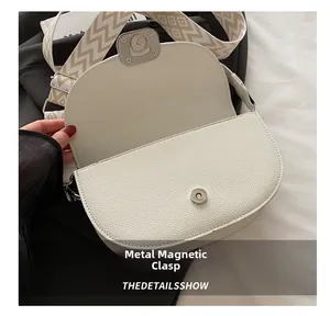 Dettaglio della borsa a sella bianca testurizzata con fibbia magnetica rotonda in metallo