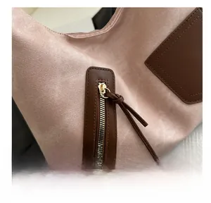 Detail der rosa Wildledertasche mit braunem Lederbesatz und goldenem Reißverschluss