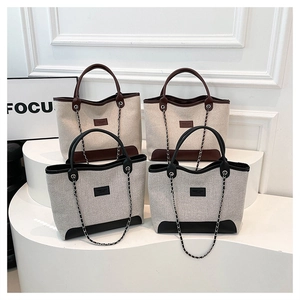 Detail view of canvas and leather patchwork tote bags with chain straps in neutral tones