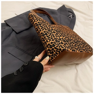 Detail view of large leopard print tote bag with brown leather base and side stitching