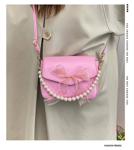 Detailed view of pink crossbody bag with tulle bow and elegant pearl chain accessory