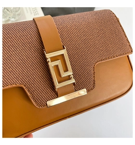 Detail of caramel brown saddle bag featuring woven fabric panel and gold geometric buckle