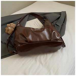 Detail view of dark brown high-shine leather hobo bag with a cute plush bear charm