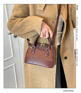 Detailed close-up of dark caramel shell bag with embossed vine texture and gold zipper
