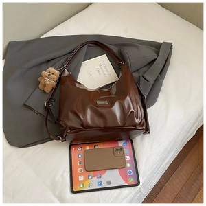 Flat lay of a large brown faux leather tote bag with plush bear charm and accessories