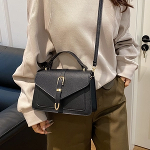 Classic black textured leather crossbody bag with belt buckle detail and top handle