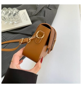 Detailed side view of brown leather saddle bag with gold hardware and precise stitching