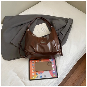 Flat lay of brown oil wax leather hobo bag on grey suit with tablet and lifestyle props