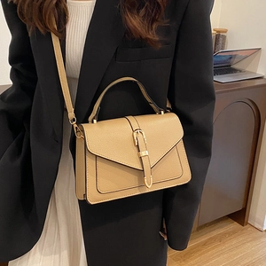Khaki pebbled leather crossbody bag with envelope flap and gold buckle on black blazer