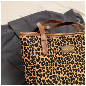 Detail of leopard print canvas tote bag with brown leather handles and fashion logo