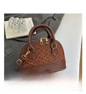 Detail of brown shell-shaped crossbody bag with geometric embroidery and golden zippers