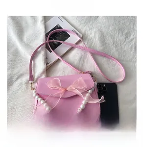 Pink shoulder bag with organza bow and white imitation pearl chain on white background