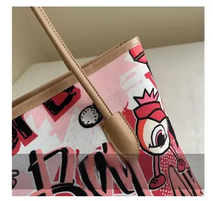 Close-up of canvas tote bag stitching with leather handles and graffiti print details