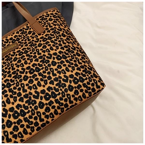 Detail view of large leopard print tote bag with brown leather handles and fashion label