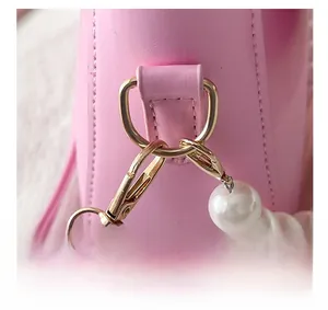 Detail of pink leather bag featuring golden D-ring hardware and white pearl chain strap