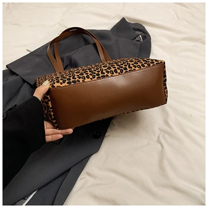 Detail of leopard print tote bag with brown leather base and sturdy stitching accents