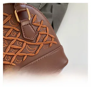 Close-up of brown embroidered shell bag with luxury texture and gold hardware details