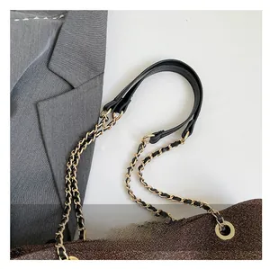 Detail of dark brown glitter bag featuring a black leather handle and gold chain strap