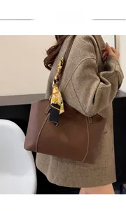 Détail du cabas en cuir marron foncé avec coutures blanches et foulard sur l'anse