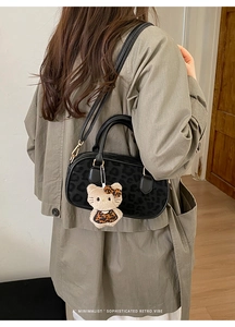 Dettaglio borsa nera con stampa leopardata e ciondolo in peluche coordinato e manici