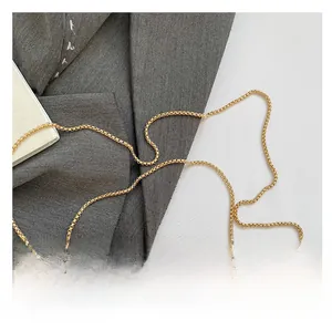 Detailed view of polished gold acrylic bag with shiny metallic bead chain handle