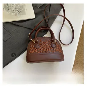 Deep brown shell bag with vintage embroidery shown next to a smartphone for size reference