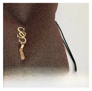 Close-up of brown glitter fabric tote with gold S-shaped hardware and chain fringe