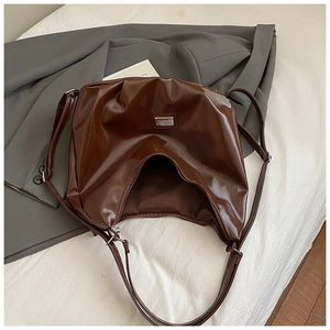 Detailed view of the brown soft PU leather texture and silver logo on the tote bag