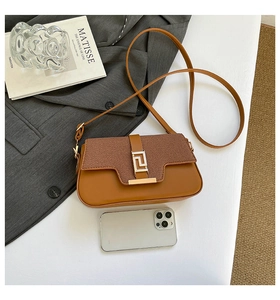 Detailed view of brown two-tone crossbody bag with gold buckle and smartphone for size scale