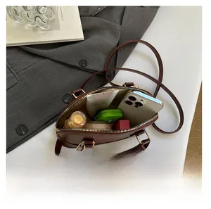 Detail view of deep brown shell bag interior showing storage space for essentials