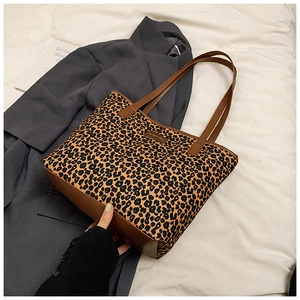 Close-up of leopard print tote bag with brown leather handles on a grey suit blazer