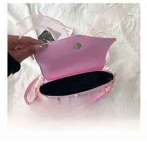 Detail view of pink crossbody bag with pearl accents and a sheer bow showing interior