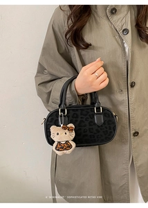 Dettaglio della borsa nera minimalista con trama leopardata e ciondolo a forma di gatto