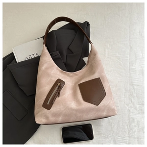 Detail einer hellrosa Tragetasche mit braunen Kontrastgriffen und Ziertaschen