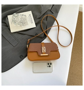 Detailed top view of a brown saddle bag with gold metal buckle on a white minimalist table