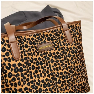 Detail of leopard print tote bag with brown leather handles and fashion logo tag