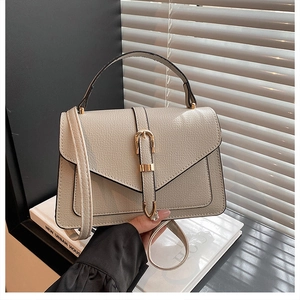 Minimalist beige pebble leather crossbody bag with vintage gold belt buckle detail