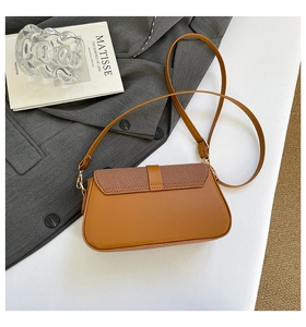 Detail of caramel leather saddle bag with twill fabric flap and gold hardware