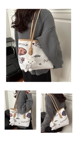 Detail of white canvas tote bag featuring astronaut prints and a plush cloud charm