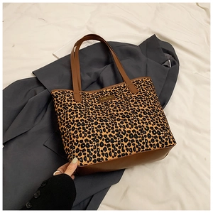 Close-up of leopard print tote bag with brown leather trim and metal Fashion tag